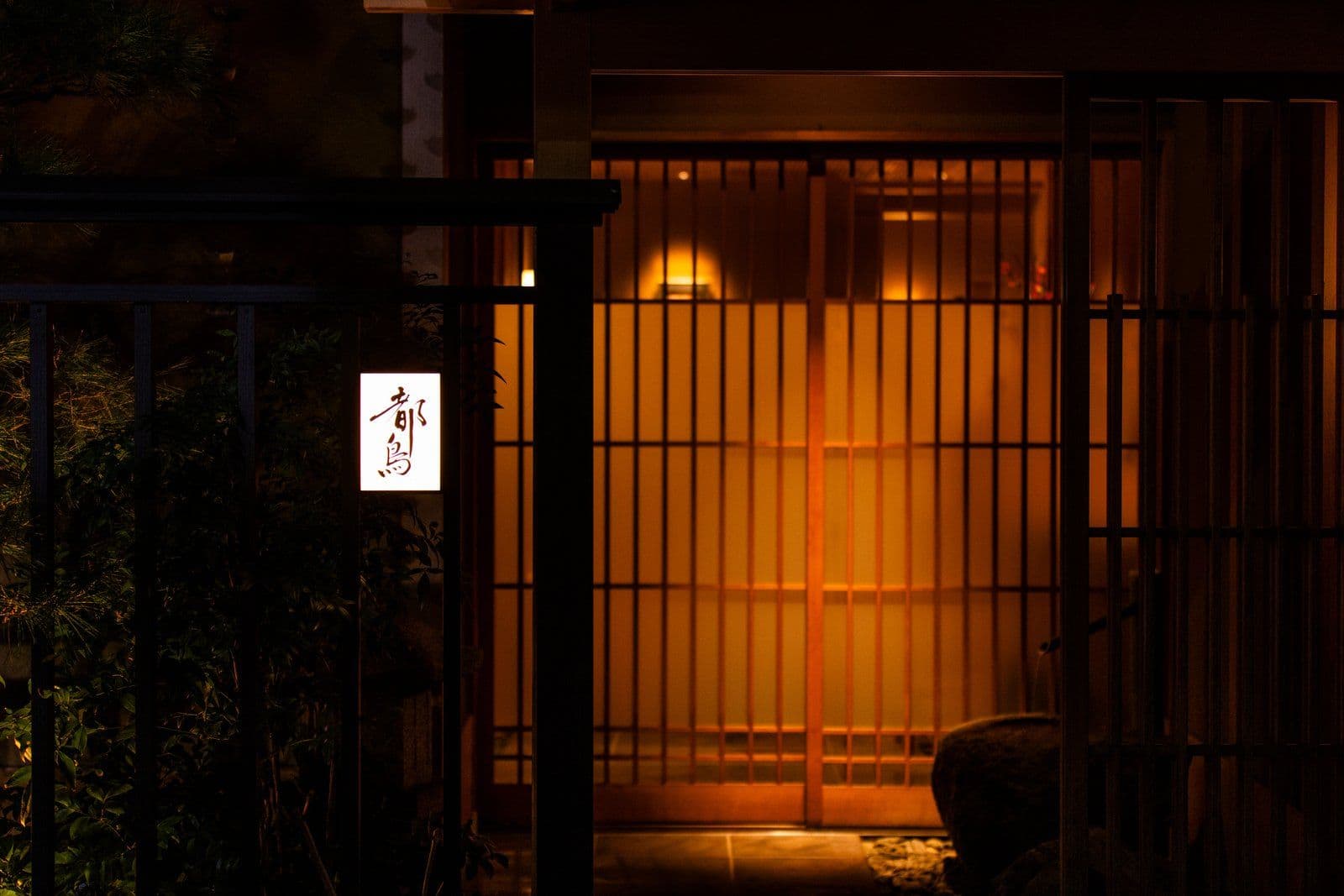 夜晚的都鳥入口:亮著燈的格子門,以及發光招牌上的店名。