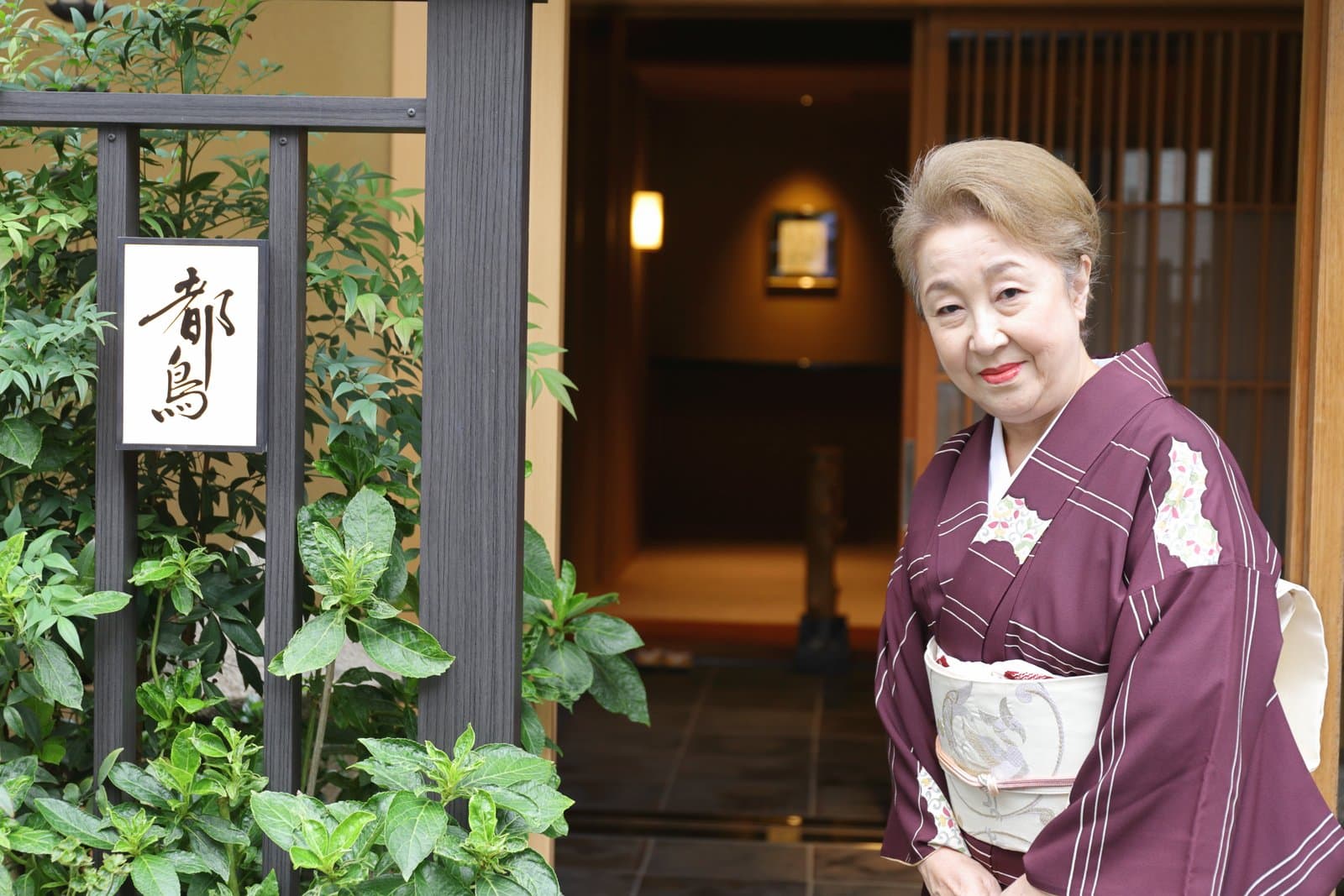 Miyakodori(都鳥)的女將千景,站在店門口的店名牌旁。