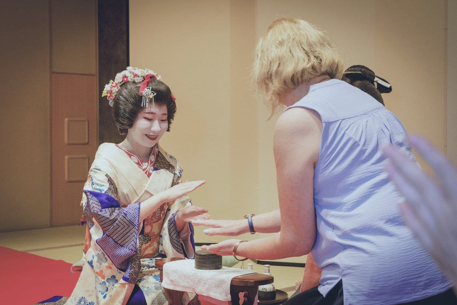 一位穿鮮豔和服的年輕藝妓與一位賓客玩「金毘羅船船」,從賓客背後拍攝。